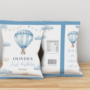 May include: A light blue and white chip bag with a watercolor hot air balloon design. The bag features the text "OLIVER'S First birthday" and "18.10.202X". The back of the bag has a nutrition facts label and the text "Thank you for celebrating with me!"