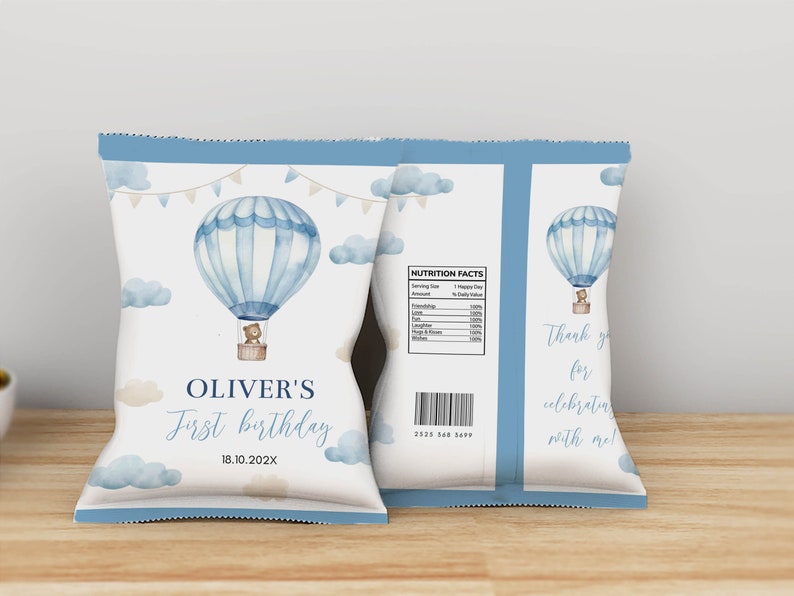May include: A light blue and white chip bag with a watercolor hot air balloon design. The bag features the text "OLIVER'S First birthday" and "18.10.202X". The back of the bag has a nutrition facts label and the text "Thank you for celebrating with me!"