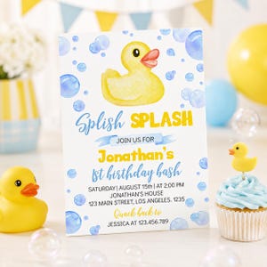 May include: A birthday invitation with a yellow rubber duck illustration and blue bubbles. The invitation reads "Splish Splash" and invites guests to Jonathan's 1st birthday bash. A cupcake with a rubber duck topper is also visible.