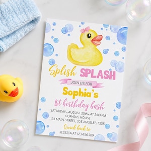 May include: A rectangular birthday invitation card featuring a yellow rubber duck with a pink bow, blue watercolor bubbles, and the text Splish SPLASH JOIN US FOR Sophia's 1st birthday bash SATURDAY AUGUST 20th AT 2:00 PM SOPHIA'S HOUSE 123 MAIN STREET LOS ANGELES 1235 Quack back to JESSICA AT 123.456.789.