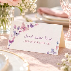 Peut inclure: Une carte blanche pli&eacute;e &agrave; la surface textur&eacute;e orn&eacute;e d'illustrations &agrave; l'aquarelle de papillons violets et roses. Le texte indique Food name here et EDITABLE TEMPLATE dans une police script et sans-serif violette, dispos&eacute;s en coin.