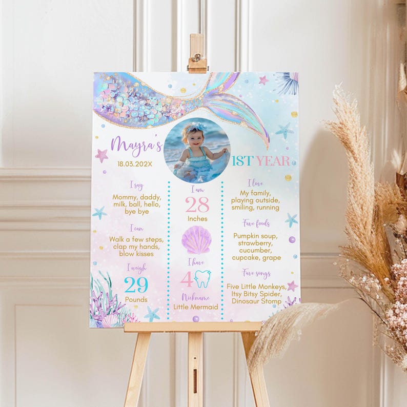 May include: A blue and purple mermaid-themed first birthday milestone poster with a photo of a baby girl. The poster includes the baby's name, Mayra, and details about her first year, including her age, height, weight, and favorite foods and songs.