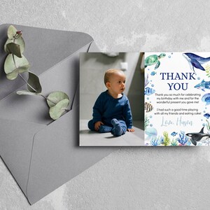 May include: A rectangular thank you card featuring a photograph of a toddler in a blue outfit on the left and watercolor illustrations of sea creatures including a whale, shark, turtle, and jellyfish on the right with the text Thank You.