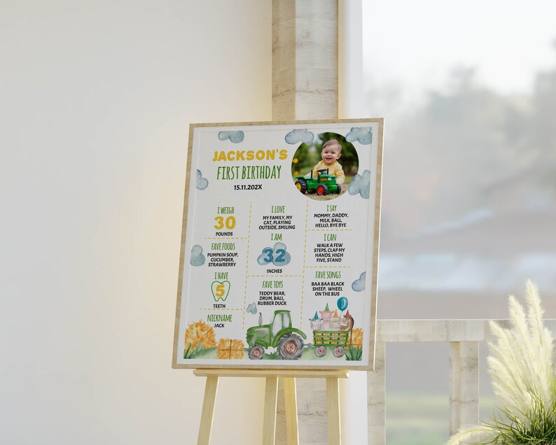 May include: A colorful first birthday poster with a photo of a baby boy in a green tractor. The poster includes details about the baby's age, weight, height, favorite foods, and toys. The poster is decorated with a tractor, hay bales, and clouds.