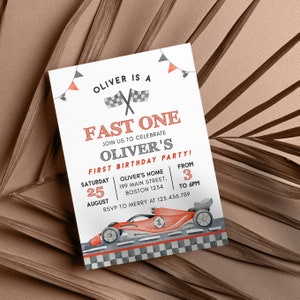 May include: A watercolor-style invitation for a first birthday party. The design features a red race car, checkered flags, and the text "Oliver is a Fast One." The invitation includes the date, time, and location of the party.