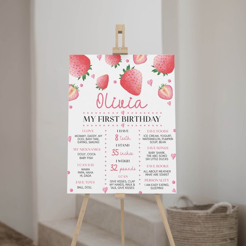 May include: A white rectangular birthday milestone sign featuring watercolor strawberry illustrations and pink hearts. The text reads Olivia, My First Birthday, and lists personal details including 8 teeth, 35 inches, and 32 pounds in pink and black font.