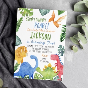 May include: A rectangular birthday invitation card featuring watercolor illustrations of a yellow triceratops, blue long-neck dinosaur, green stegosaurus, red dinosaur, and orange pterodactyl surrounded by green tropical leaves and text.