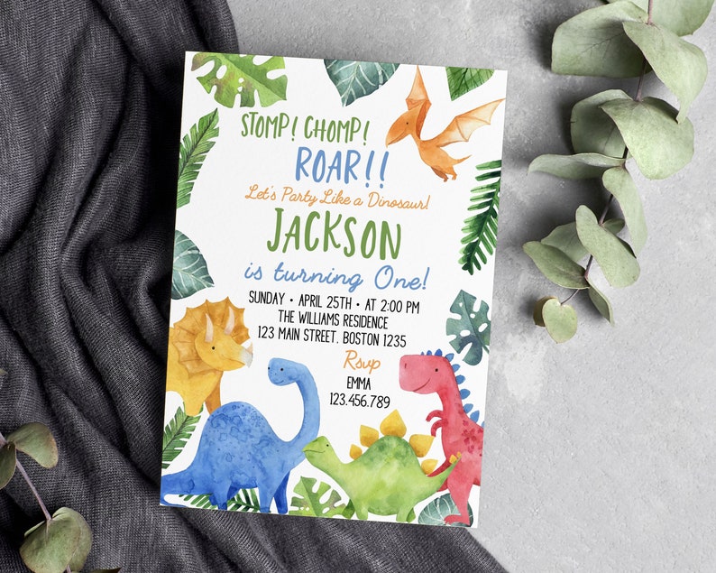 May include: A rectangular birthday invitation card featuring watercolor illustrations of a yellow triceratops, blue long-neck dinosaur, green stegosaurus, red dinosaur, and orange pterodactyl surrounded by green tropical leaves and text.