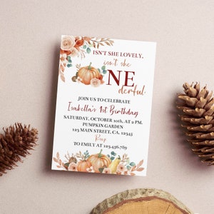 May include: A rectangular birthday invitation card featuring watercolour illustrations of pumpkins, autumn leaves, and flowers. The text reads: ISN'T SHE LOVELY, isn't she ONEderful. JOIN US TO CELEBRATE Isabella's 1st Birthday, SATURDAY, OCTOBER 10th, AT 2 PM.