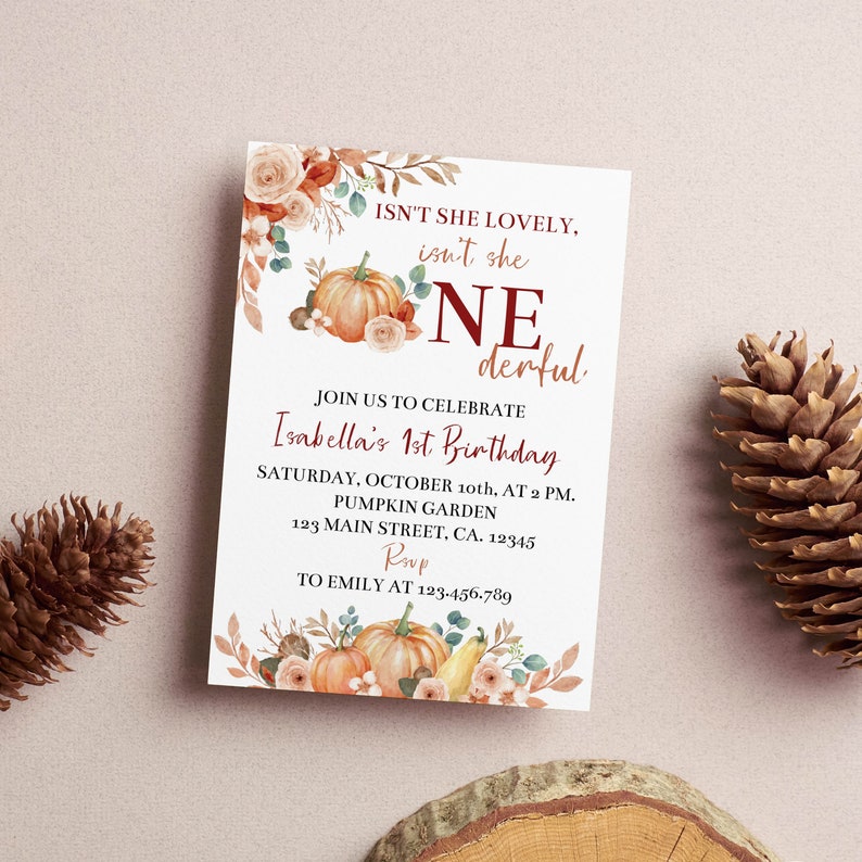 May include: A rectangular birthday invitation card featuring watercolour illustrations of pumpkins, autumn leaves, and flowers. The text reads: ISN'T SHE LOVELY, isn't she ONEderful. JOIN US TO CELEBRATE Isabella's 1st Birthday, SATURDAY, OCTOBER 10th, AT 2 PM.