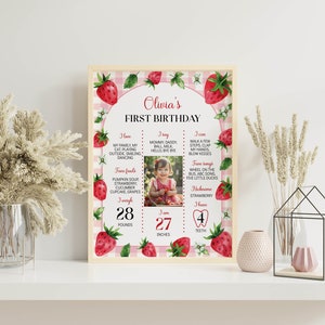 May include: A pink and white gingham background with a strawberry theme. The text "Olivia's First Birthday" is at the top. The poster includes a photo of a baby girl, her weight and height, and a list of things she can do and eat.