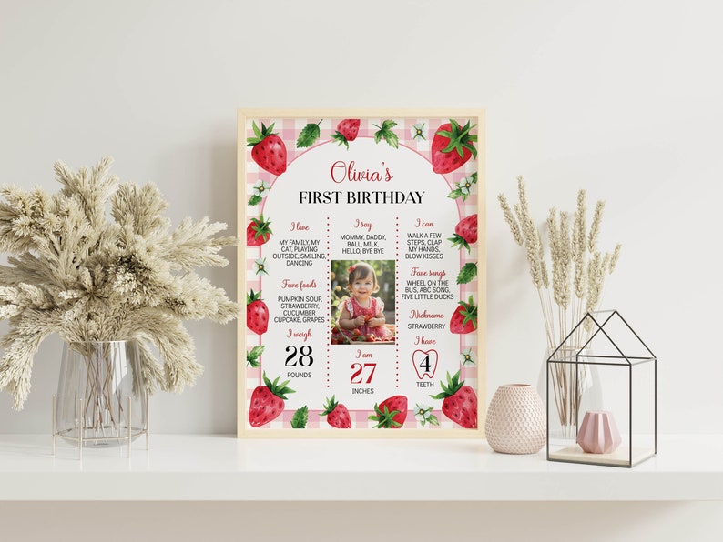 May include: A pink and white gingham background with a strawberry theme. The text "Olivia's First Birthday" is at the top. The poster includes a photo of a baby girl, her weight and height, and a list of things she can do and eat.