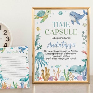 May include: A blue and green time capsule sign with a watercolor illustration of sea creatures. The sign says "Time Capsule" and "To be opened when Amelia turns 18". There is a blank card with lines for writing a message to Amelia.