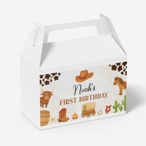 Puede incluir: Una caja de cart&oacute;n blanca con asa y un estampado de tem&aacute;tica western que incluye manchas de vaca, un sombrero de vaquero, un toro, un caballo, un barril, una bota, una carreta, un cactus y el texto Noah's FIRST BIRTHDAY en letras marrones.