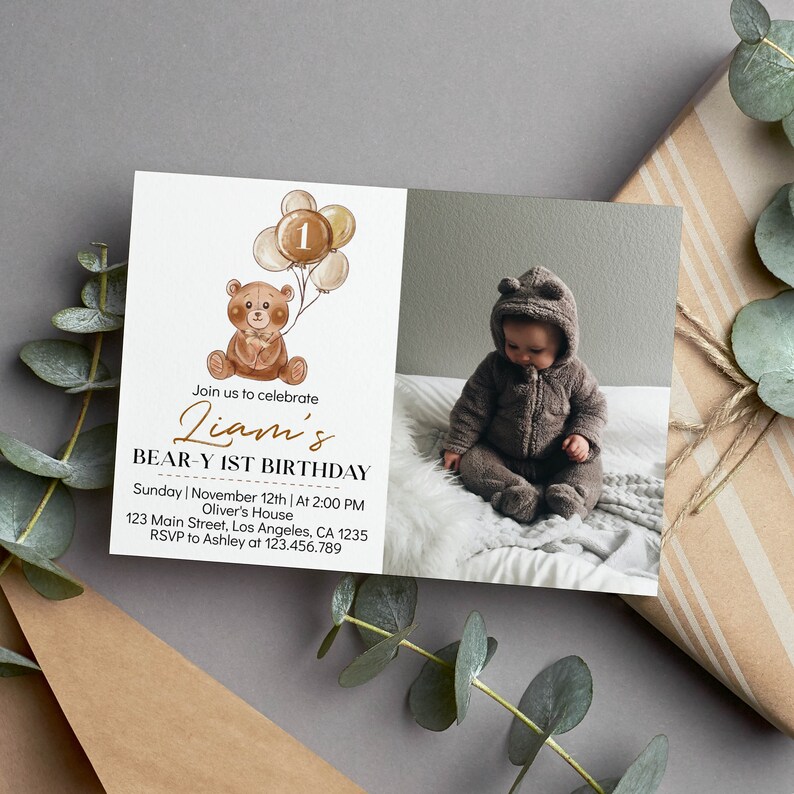 Op de afbeelding: Een rechthoekige uitnodigingskaart met een aquarelillustratie van een bruine teddybeer die een tros ballonnen met het cijfer 1 vasthoudt. De tekst luidt Liam's BEAR-Y 1ST BIRTHDAY, Sunday November 12th, 2:00 PM, Oliver's House, 123 Main Street, Los Angeles, CA 1235, RSVP to Ashley at 123.456.789. Rechts staat een foto van een kind in een bruine jumpsuit met een capuchon met berenoortjes.