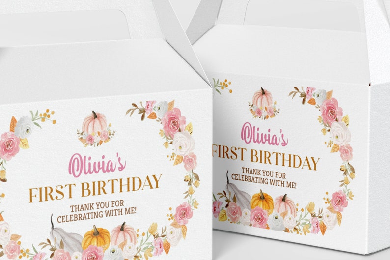 May include: Two white gable boxes featuring a floral wreath design with pink and white roses, orange and pink pumpkins, and gold text that reads Olivia's FIRST BIRTHDAY THANK YOU FOR CELEBRATING WITH ME! The boxes have a handle at the top.