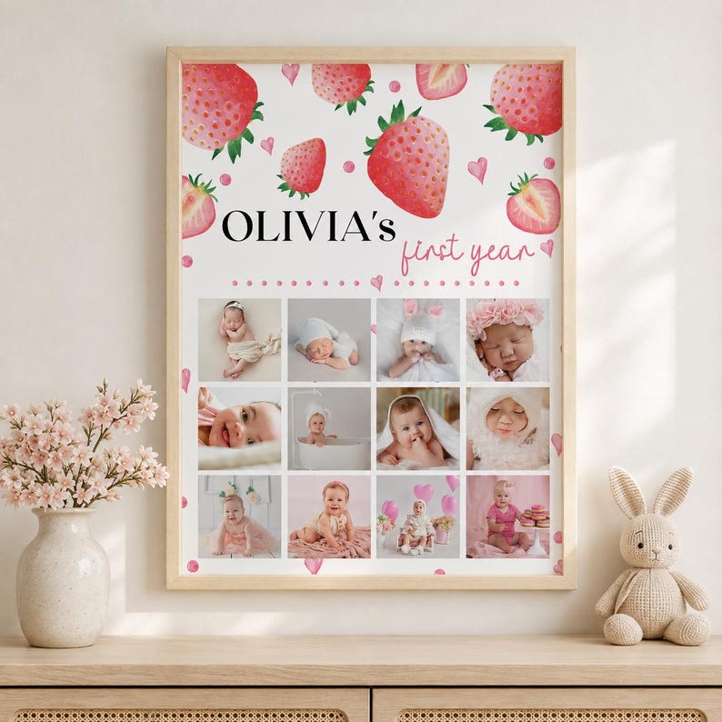 K&ouml;nnte beinhalten: Ein rechteckiges Wandposter mit wei&szlig;em Hintergrund, Aquarell-Erdbeerillustrationen und kleinen rosa Herzen. Der Text OLIVIA'S first year steht &uuml;ber einem Raster aus zw&ouml;lf einzelnen Fotos eines Babys in verschiedenen Posen.
