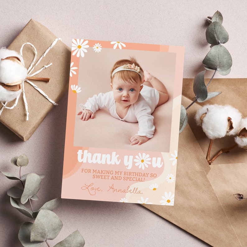 May include: A rectangular thank you card featuring a photo of a baby in a white long-sleeve shirt and headband. The card has a peach background with white daisy illustrations and the text: thank you FOR MAKING MY BIRTHDAY SO SWEET AND SPECIAL! Love, Annabella.