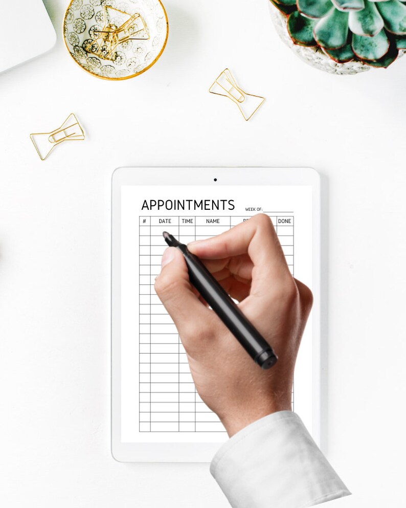 May include: A white tablet with a black grid and the text "APPOINTMENTS" at the top. A hand is holding a black marker and writing on the tablet.