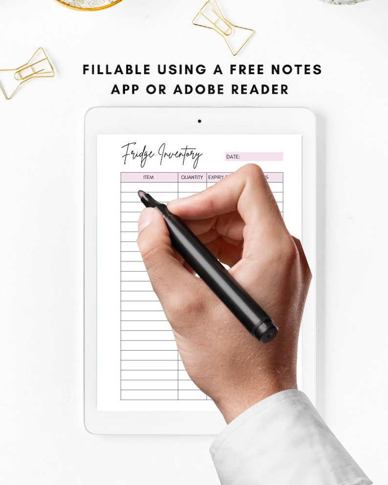 May include: A digital tablet displaying a printable fridge inventory list. The list has columns for item, quantity, expiry date, and notes. A hand is holding a black marker pen and writing on the tablet screen.