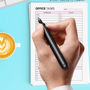 Op de afbeelding: Een hand met een zwarte marker boven een afgedrukte "Office Tasks" planner. De planner heeft een roze kop en schema-secties. De tekst "Print at home and start using it today" staat bovenaan. Een kopje koffie en een toetsenbord staan op de achtergrond.