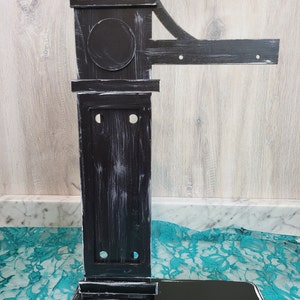 May include: Black wooden stand with a decorative top and a base. The stand has a distressed finish with white paint showing through the black paint.