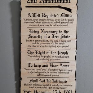 May include: A wooden sign with the text "2nd Amendment" and the text of the Second Amendment of the United States Constitution. The sign is decorated with a stylized image of a musket.