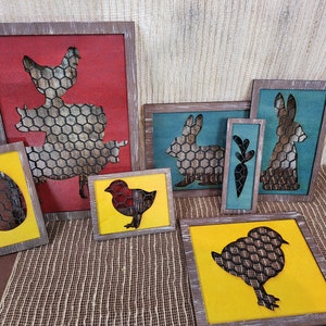 May include: Set of seven wooden framed wall decor pieces with a farmhouse theme. The frames are painted in shades of red, yellow, blue and green. Each frame features a silhouette of a farm animal or egg with a chicken wire pattern.
