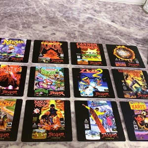 May include: A set of 12 black coasters featuring different video game covers for the Atari Jaguar console. The coasters feature games like Rayman, Cannon Fodder, and Wolfenstein 3D.