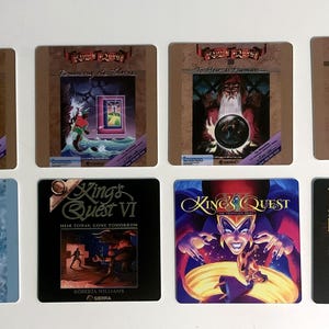 May include: Eight square coasters featuring King's Quest video game cover art. The top row displays King's Quest I through IV, while the bottom row shows King's Quest V, VI, VII, and Mask of Eternity. Each coaster features the game title and artwork.