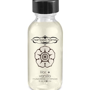 May include: A clear glass bottle with a black lid and label. The label says "namaste home" and "lilac + vanilla multipurpose concentrate 1 oz / 30 ml".
