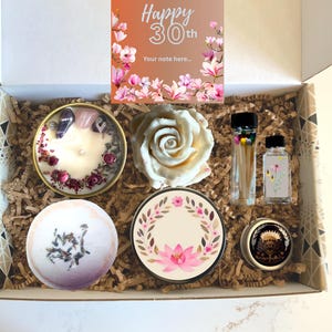Könnte beinhalten: Geschenkbox mit Kerze, Badekugel und dekorativer Rose. Die Box enthält eine Karte mit der Aufschrift "Happy 30th". Die Artikel sind auf einem Bett aus braunem Papier angeordnet. Die Box ist mit einem geometrischen Muster verziert.