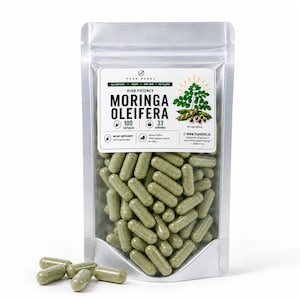 May include: A transparent pouch containing green capsules, with the text "MORINGA OLEIFERA." The label indicates 100 capsules and 33 servings, with the brand name "PEAK HERBS." Several capsules are scattered in front of the pouch.