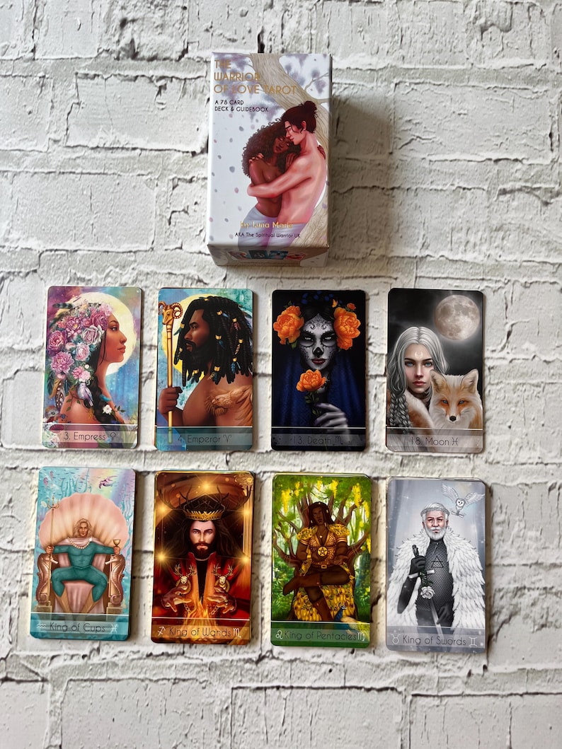 Puede incluir: Un juego de cartas del tarot y un juego de gu&iacute;as con ilustraciones coloridas. La caja muestra a una pareja abraz&aacute;ndose. Se muestran varias cartas del tarot, incluyendo la Emperatriz, el Emperador, la Muerte, la Luna, el Rey de Copas, el Rey de Bastos, el Rey de Oros y el Rey de Espadas.