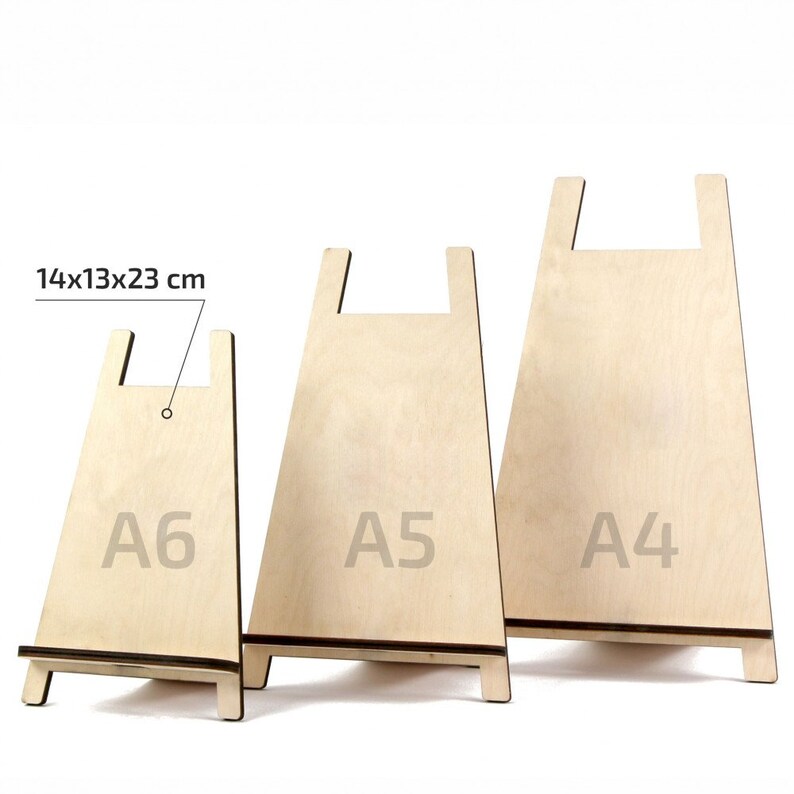 May include: Three wooden display stands in A6, A5, and A4 sizes. The stands are made of light-coloured wood and have a simple, minimalist design. The smallest stand measures 14 x 13 x 23 cm. The stands are ideal for displaying artwork, photos, or other items.