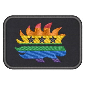 Könnte beinhalten: Ein schwarzer gestickter Aufnäher mit einem stilisierten Flammenmotiv in Regenbogenfarben und drei schwarzen Sternen. Das Flammenmotiv erinnert an einen Stachelschwein.