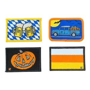 May include: Four embroidered patches. One shows beer steins, another a blue truck with pumpkins, a jack-o'-lantern, and a candy corn design. Each patch has a coloured border and is set against a white background.