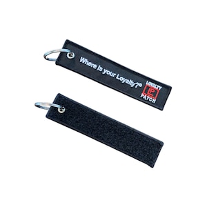 May include: Two black rectangular keyrings with silver key rings. One keyring has the text "Where is your Loyalty?" and the "Loyalty Patch" logo in red and white. The other keyring has a velcro surface.