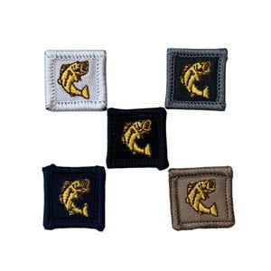 May include: Five square embroidered patches featuring a yellow fish design. The patches are in various colors: white, gray, black, navy blue, and tan. The fish design is consistent across all patches.