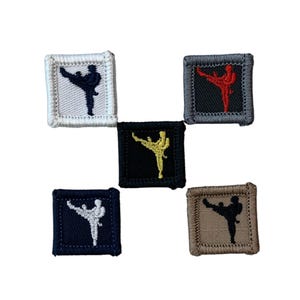 Puede incluir: Cinco parches cuadrados bordados con una figura de artes marciales. Los parches son de varios colores: blanco, gris, negro, azul marino y beige. La figura está representada en negro, blanco, rojo o amarillo. Cada parche tiene un borde contrastante.