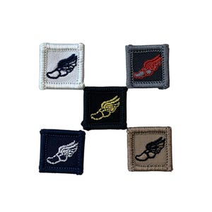 May include: Five embroidered patches in various colors: white, black, navy, gray, and tan. Each patch features a winged foot design in a contrasting color. The patches are square with a stitched border.