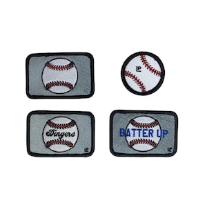 May include: Four embroidered patches featuring baseball designs. One circular patch shows a baseball, while three rectangular patches feature baseballs with the text Dingers, Batter Up, or no text, all set against a grey background with black borders.