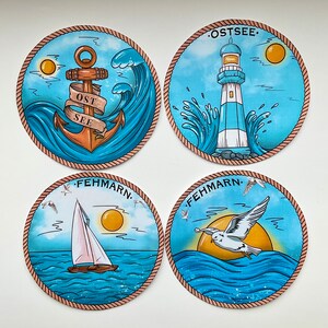 Puede incluir: Cuatro pegatinas redondas y coloridas con temas náuticos. Cada pegatina presenta un diseño diferente: un ancla con las palabras "Ost See", un faro con las palabras "Ostsee", un velero con las palabras "Fehmarn" y una gaviota con las palabras "Fehmarn".