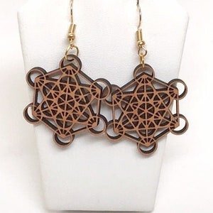 May include: A pair of wooden earrings with a geometric design. The earrings are brown and have a gold-colored hook.