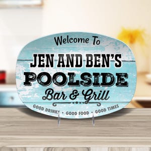 May include: A blue and white oval-shaped sign with the text "Welcome To Jen And Ben's Poolside Bar & Grill Good Drinks Good Food Good Times".