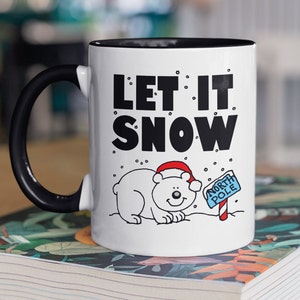 May include: White ceramic mug with a black rim and handle. The mug has a black and white illustration of a polar bear wearing a Santa hat and a sign that says "North Pole". The text "Let it snow" is printed in black on the mug.