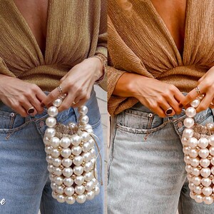 May include: A woman is wearing a gold sparkly top and blue jeans. She is holding a white pearl bag with a gold drawstring. The bag is made of large, round pearls.