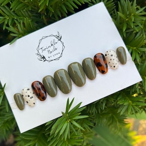 May include: Set of ten press-on nails with a green base color. Some nails have a brown and white leopard print design, while others have a white base with black polka dots.