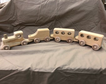 May include: A wooden toy train set with a locomotive and three passenger cars. The train is made of natural wood and has a rustic, handmade look.