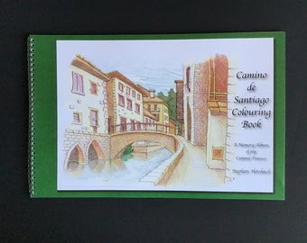 May include: A green spiral bound coloring book with a hand-drawn illustration of a bridge and buildings. The title is "Camino de Santiago Coloring Book" and the subtitle is "A Memory Album of the Camino Frances".